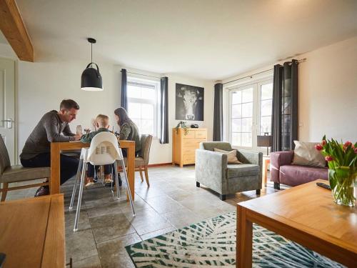 罗赫尔Child-friendly villa with large garden in Limburg的两个男人和一个孩子坐在客厅的桌子上