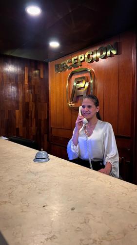 MéridaPark Hotel Mérida的坐在一张桌子旁的一位女士,在手机上讲话