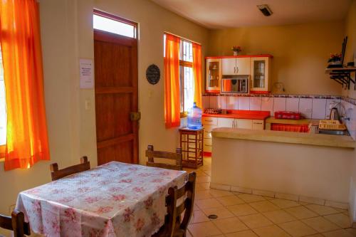 曼克拉Hospedaje Guadalupe Inn的一间带桌子的厨房和一间带橙色窗帘的厨房