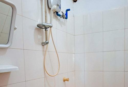 卢纳将军城RedDoorz @ Hergem Siargao Inn的白色瓷砖浴室内带软管的淋浴