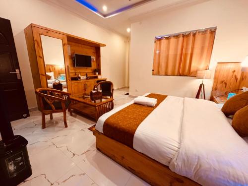 朱纳格特Siluswar Hotel的一间卧室配有一张床、一张书桌和一台电视