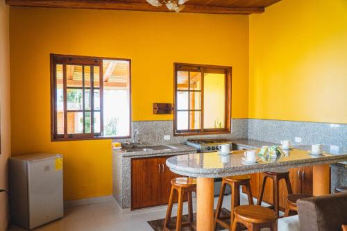 奥塔瓦洛Hospedaje Cabaña Familiar的厨房设有黄色的墙壁和一张桌子及凳子