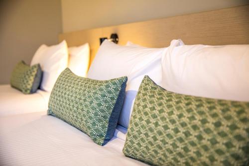 汤斯维尔Nightcap at Dalrymple Hotel的一张带白色枕头和绿色枕头的床