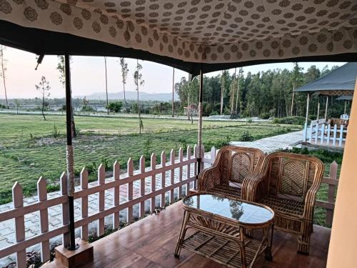 萨哈兰普尔Pulastya Wellness Resort的门廊配有两把椅子和一张桌子,并拥有围栏