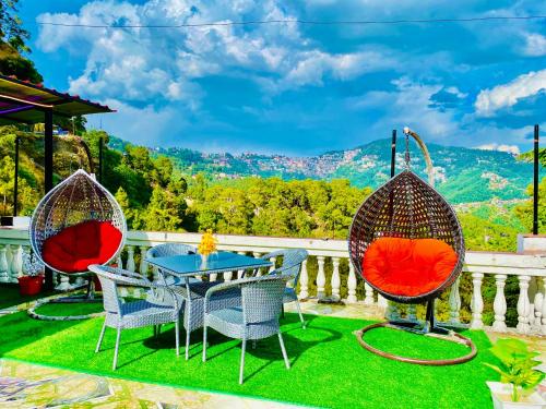 西姆拉Hotel Tara Regency - A family Hotel的庭院设有三把椅子和一张桌子,享有美景。