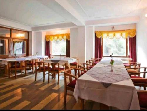 西姆拉Hotel Tara Regency - A family Hotel的用餐室设有桌椅和窗户。
