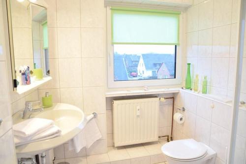 韦斯特兰Krabbenliebe的一间带水槽和卫生间的浴室以及窗户。
