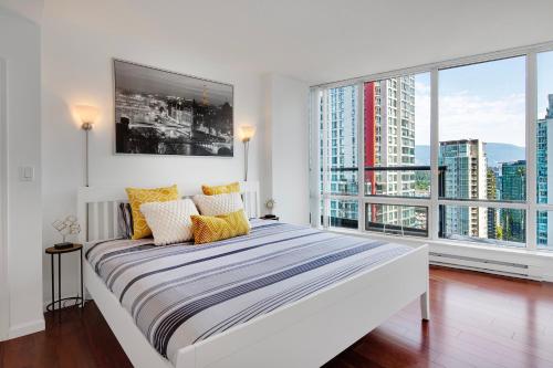 温哥华Designer sub-penthouse - Central Downtown Views And King Bed!的白色卧室设有大床和大窗户