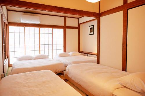 东京1stop to Shibuya station Japanese traditional house的带窗户的客房内的三张床