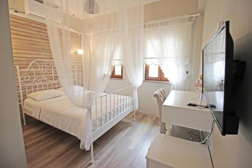 博兹贾阿达岛Karina Vineyard House的白色卧室配有婴儿床和书桌