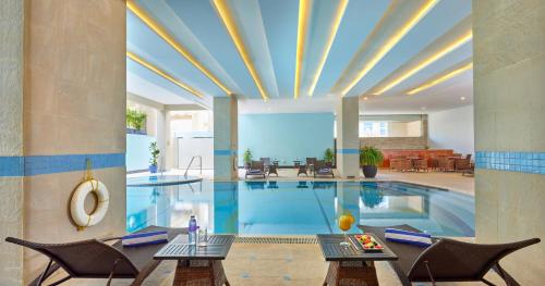 迪拜Flora Creek Deluxe Hotel Apartments, Deira的一个带2张桌子和椅子的大型游泳池