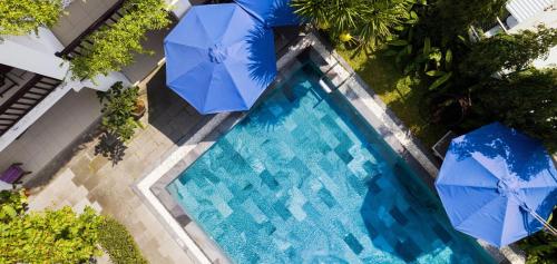 会安Golden Pearl Hoi An Hotel的享有带两把蓝伞的游泳池的顶部景致