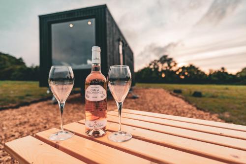 彼得斯菲尔德OffGrid Tiny Home W/ View Of South Downs NP的木桌旁的一瓶葡萄酒和两杯酒