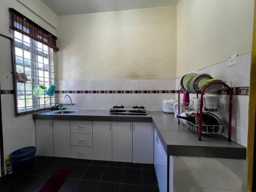 瓜拉丁加奴Dhiaa Homestay D Jembal的厨房配有白色橱柜、水槽和窗户。