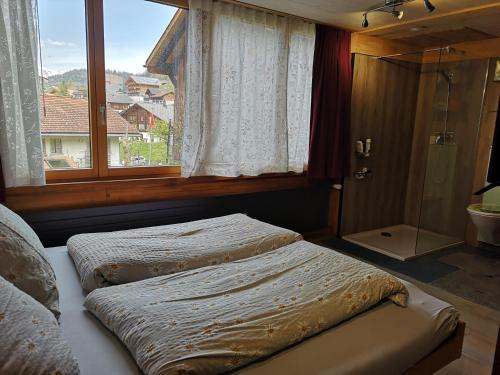 哈斯利伯格Ritterstübli的一间卧室设有两张床和一间带淋浴的窗户。