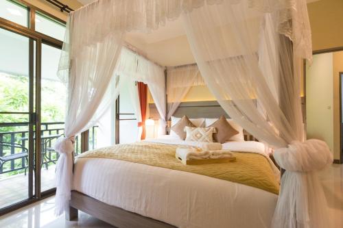清迈Radateeree Boutique Resort的卧室配有带白色窗帘的天蓬床