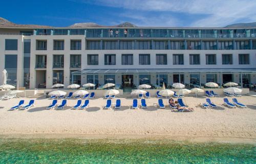斯拉诺阿德默勒尔大酒店的海滩上的一组椅子和遮阳伞