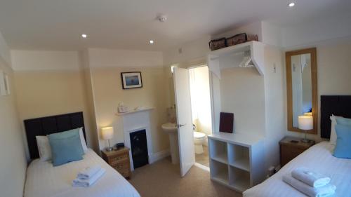 莱姆里吉斯Charnwood Guest House的一间带两张床的卧室和一间浴室