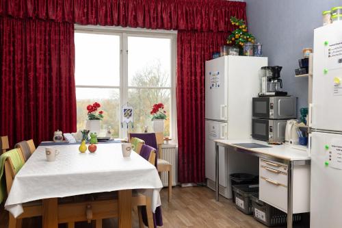 ErvallaChristinas Gästgifveri B&B的一间带白色桌子的厨房和一间带红色窗帘的厨房