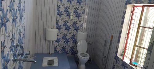 德奥加尔Anand Bhavan的浴室设有卫生间,并装饰有蓝色和白色的壁纸。