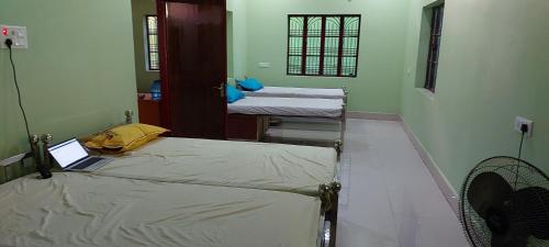 德奥加尔Anand Bhavan的一间设有两张床的房间,上面有一台笔记本电脑
