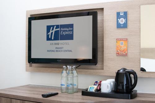 芭东海滩Holiday Inn Express Phuket Patong Beach Central, an IHG Hotel的一间酒店客房的架子上配有平面电视