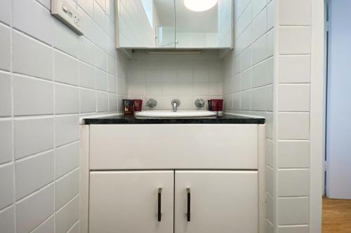 悉尼Ocean view Clovelly的一间带水槽和白色橱柜的浴室
