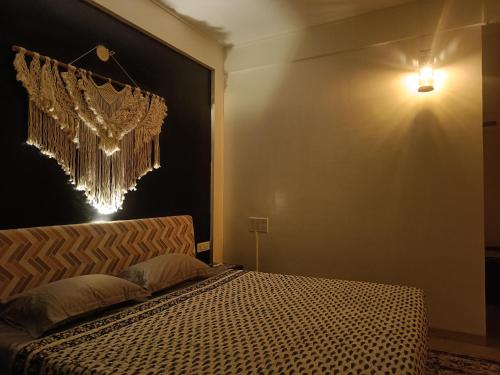 浦那Nagarik Commune, Baner - Pune的卧室配有一张床,墙上挂着吊灯