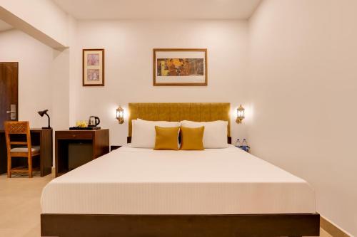达博利Lemon Tree Hotel, Dapoli的一间卧室配有一张带黄色枕头的大床