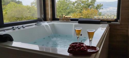 科维良Villa Regadio的浴缸配有两杯香槟酒和一碗水果