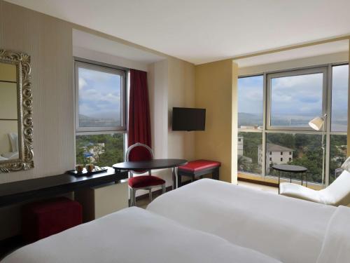 金沙萨金沙萨格兰德铂尔曼酒店的酒店客房设有一张床、一张书桌和窗户。