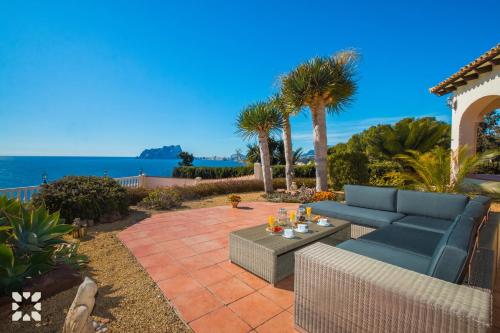 特乌拉达Villa Blue Sea by Abahana Villas的天井配有蓝色的沙发和桌子