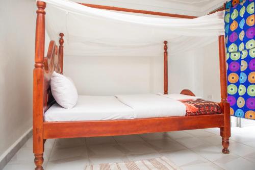 波特尔堡KaribuGuestHouse的一间卧室配有一张带白色床单的木床