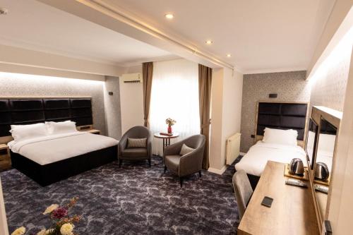 PelitliCOMFORT HOUSE HOTEL的酒店客房带两张床和一张桌子以及椅子。
