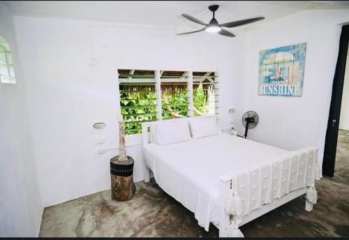 EtonBanana Bay Beach Club的白色卧室配有白色的床和吊扇