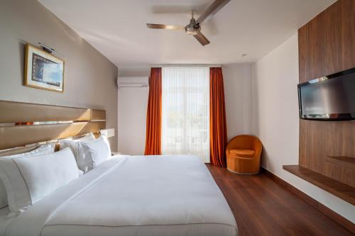 AyodhyaCountry Inn Anant Ayodhya的卧室设有一张白色大床和一扇窗户。