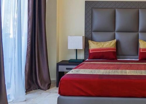 达喀尔Hôtel Bachou的一间卧室配有一张带红色毯子和灯的床
