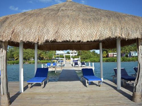 库尔克岛Caribbean Beach Suite的一个带蓝色椅子和草伞的码头