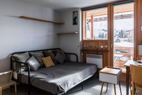 阿沃里亚兹IMMODREAMS - La Tanière - Avoriaz的一间卧室配有一张床、一张桌子和一个窗户。