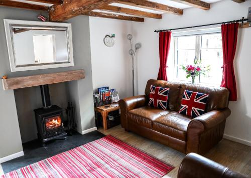 绍斯韦尔Southwell Holiday Cottage - Lavender Cottage的客厅设有真皮沙发和壁炉