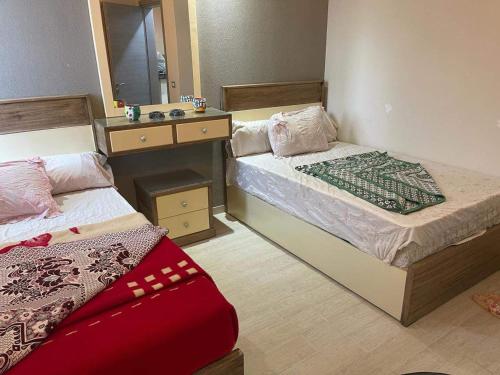 艾因苏赫纳Ilmontegalala的一间卧室设有两张床、镜子和水槽