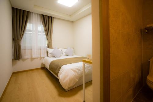 首尔荣耀旅馆的一间小卧室,配有床和窗户