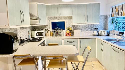 彼得伯勒Magnolia的厨房配有白色橱柜和桌椅