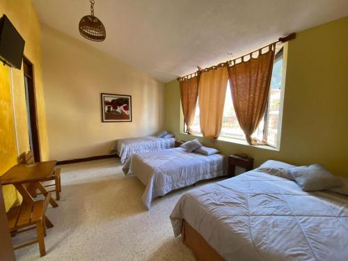 La AuroraHOTEL IXBALANQUE的一间卧室配有两张床、一张桌子和两个窗户。