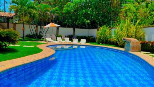 贝贝里比Pousada Villa Mariposa的庭院内的游泳池配有椅子和遮阳伞