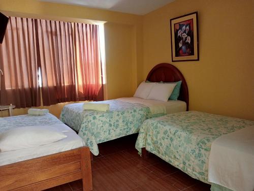 齐克拉约Hotel San Eduardo的酒店客房设有两张床和窗户。