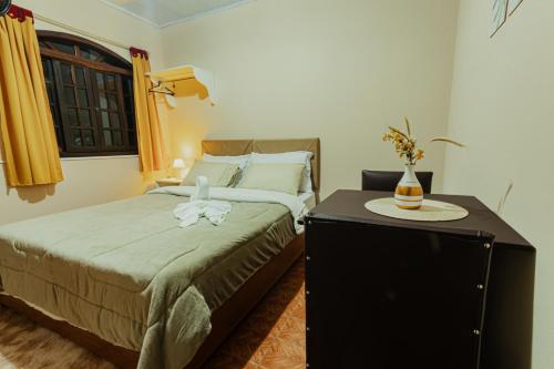 圣安东尼奥-杜皮尼亚尔Pousada São Benedito的一间卧室配有一张床和一个带桌子的梳妆台