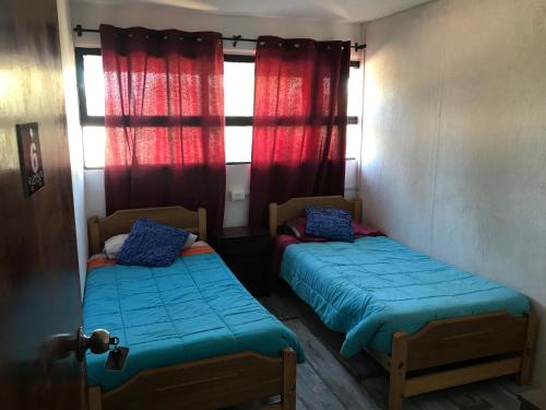 卡萨布兰卡Hostal Emporio的小房间设有两张床,配有红色窗帘