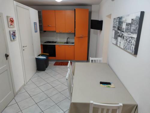 切法卢Cortile Maggiore Home的厨房配有橙色橱柜和白色的桌椅