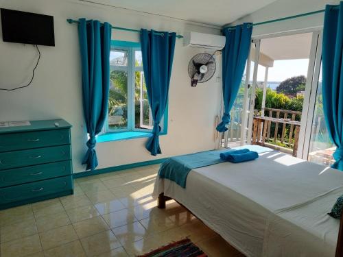 拉戈莱特Surf House的一间卧室配有蓝色窗帘、一张床和窗户